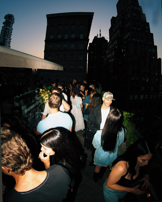 A group of people gathered on a rooftop in a city at evening