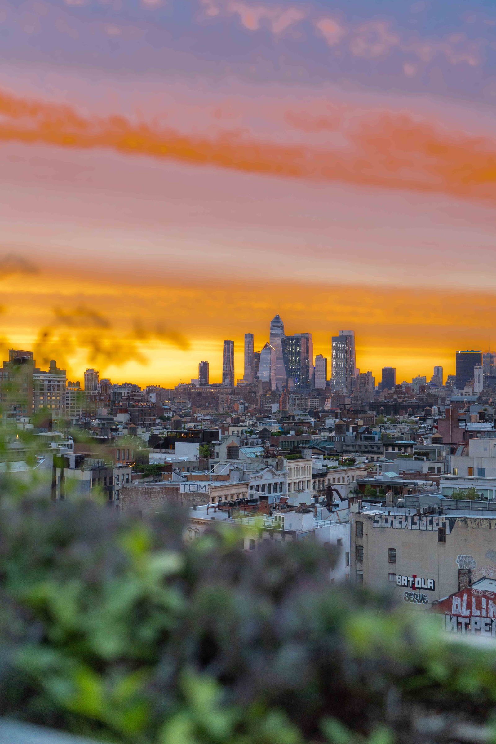 A city skyline at sunset with a vibrant orange and yellow sky